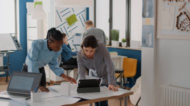 Mimarlar takımı bina yapısını tasarlamak için planlar ve tablet üzerinde çalışıyor.