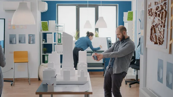 Mann entwirft mit Smartphone Baumodell und Baugrundriss im Büro — Stockfoto