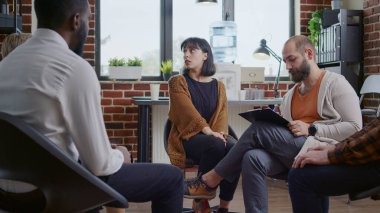 Gergin davranışlı bir kadın A.A. grup terapi seansında insanlarla zihinsel sağlık sorunları paylaşıyor.