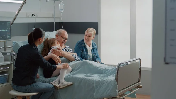 Child hugging sick grandpa in hospital ward bed at visit — Stockfoto