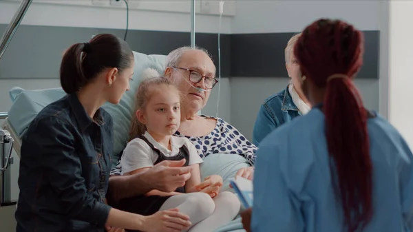 Close up of african american nurse talking to patient and his family — стоковое фото