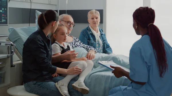 Фахівець з охорони здоров'я проводить оглядовий візит з пацієнтом та його сім'єю — стокове фото