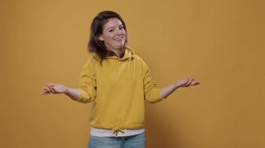Stüdyoda güler yüzlü ve misafirperver bir jest yapan dost canlısı bir kadın. Olumlu davranışları olan kapüşonlu bir genç kız. İfade veren, neşeli, sosyalleşen, el sallayan biri..