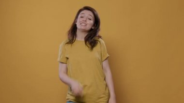 Sarı arka planda eşine olan sevgisini göstermek için el hareketleriyle kalp işareti yapan mutlu bir kadın. Sevgililer Günü 'nde gülümseyen, aşık olan, romantik konuşan kişi..