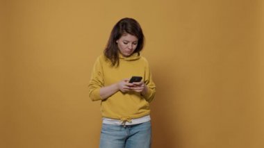 Stüdyodaki sosyal medya mesajlaşması uygulamasında elinde akıllı telefon mesajları olan sıradan bir kadının portresi. 20 'li yaşlarının sonunda dijital dokunmatik ekran cihazı kullanarak gülen biri..