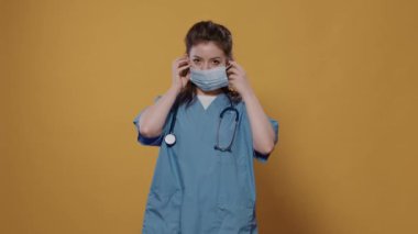 Korunmak için kovan maskesi takan kadın doktor stüdyoda kolları çapraz pozlar vererek fotokopi çekiyordu. Koruyucu üniforma ve steteskop giyen Kafkas sıhhiyesinin portresi.