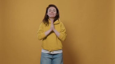 Sıradan bir kadın endişeli hisseder, dua eder ve stüdyoda avuç içleri birbirine yakın bir şekilde af diler. Kapüşonlu, dindar, umudu ve inancı olan mütevazı bir genç..