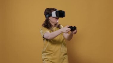 Stüdyoda video gözlük ve konsol kontrolörüyle zor seviye oyun kazanan bir kadın. Sanal gerçeklikle yoğun deneyimi olan oyuncu kız çevreyi çevreleyen 3D 'ye bakıyor..