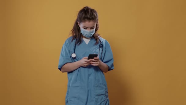 スマートフォンを持って聴診器を持つ医師やカメラで緑色の画面のモックアップを示すテキストメッセージ 病院の制服を着た医療コピースペースを提示タッチスクリーンデバイスを使用して外科用マスク — ストック動画