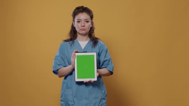 自信的医生摆出一副手持数码平板电脑的姿势 绿色屏幕造型设计 穿着医院制服在工作室里 使用触摸屏装置宣传医疗概念的女医生 — 图库视频影像
