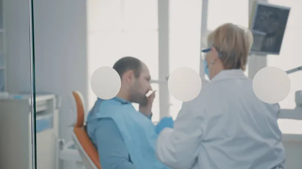 成熟した歯科医は、患者と口腔ケア相談を行う — ストック写真