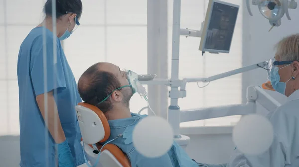 Dental assistant using oxygen mask to do anesthesia on patient — Foto Stock