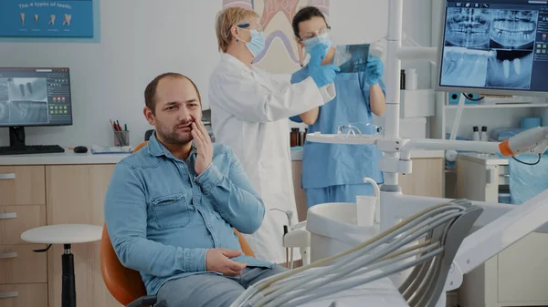 Tandheelkundige patiënt die ernstige kiespijn in het mondverzorgingskabinet uitdrukt — Stockfoto