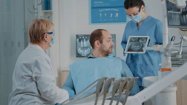 歯痛患者にX線検査結果を示す歯科医師と看護師 — ストック写真