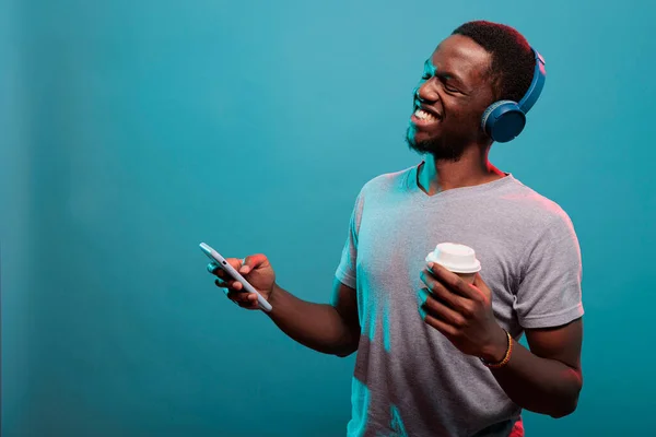 Lachende volwassene luisteren naar muziek afgespeeld op de smartphone met hoofdtelefoon — Stockfoto