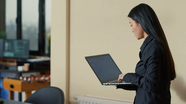 Développeur de logiciels asiatiques à venir au bureau et assis tenant ordinateur portable avec interface de codage — Photo