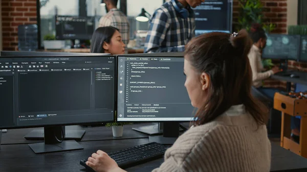 Programador de software escrevendo código na frente de várias telas de computador — Fotografia de Stock