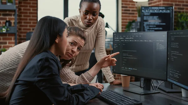 Programmateur pointant vers l'écran de l'ordinateur expliquant le code en cours d'exécution aux collègues de réflexion idées logicielles — Photo