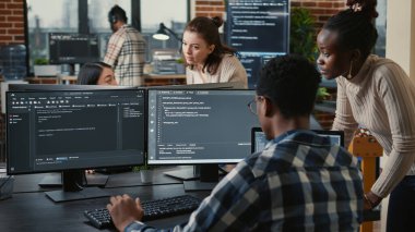 Yapay zeka bulut programcılarından oluşan karma bir ekip birden fazla ekranın önünde programlama hakkında konuşuyor.
