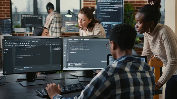 Equipe mista de programadores de nuvem de inteligência artificial falando sobre programação na frente de várias telas — Fotografia de Stock