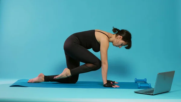 Donna attiva che allunga i muscoli delle gambe sul tappetino yoga — Foto Stock