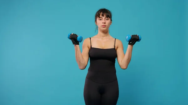 Mujer en forma levantando pesas para entrenar los músculos de los brazos delante de la cámara —  Fotos de Stock