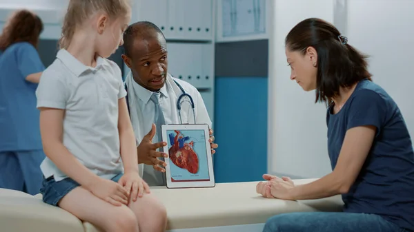 Médico mostrando imagem do coração em tablet para mulher e criança — Fotografia de Stock