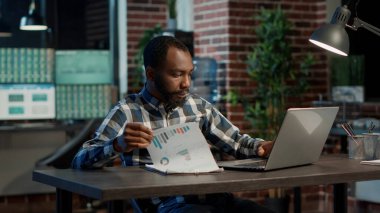 Satış danışmanı kağıt ve dizüstü bilgisayarlardaki finansal tabloları analiz ediyor.