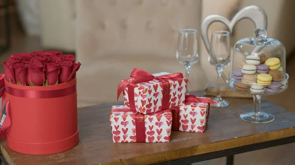 Valentinstag Geschenkboxen mit roten Herzen Geschenkpapier auf Couchtisch neben Luxus roten Rosen Bouquet — Stockfoto