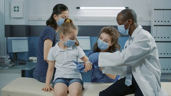 Pediatra poniendo curita en brazo lesionado de niño en consulta — Foto de Stock