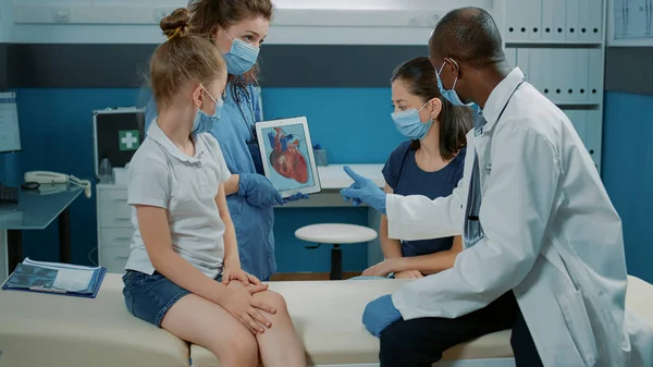 Sjuksköterska som håller kardiologi bild och medic förklara hjärtsjukdom — Stockfoto