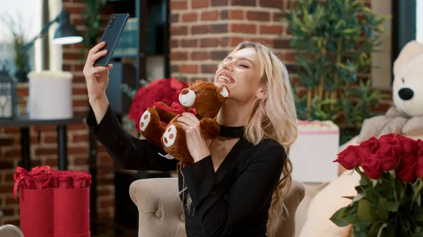 Portrait de belle femme sur la Saint-Valentin tenant smartphone prenant selfie avec cadeau ours en peluche — Photo