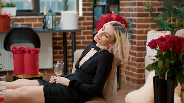 Atraktivní žena usínající na židli se sklenkou šampaňského v ruce — Stock fotografie