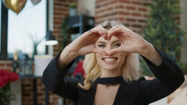 Сексуальная блондинка с вывеской в форме сердца на камере — стоковое фото