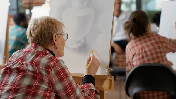 Старий студент використовує олівець, щоб намалювати модель натхнення на уроці — стокове фото
