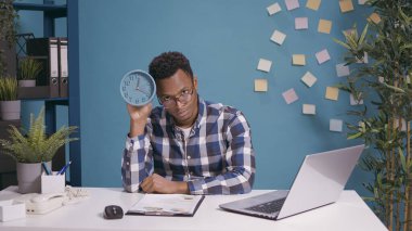 Dakik adam duvar saatini kontrol ediyor ve üzgün hissediyor.