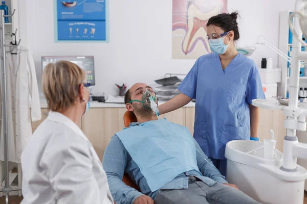 Команда ортодонтов надевает кислородную маску на пациента — стоковое фото