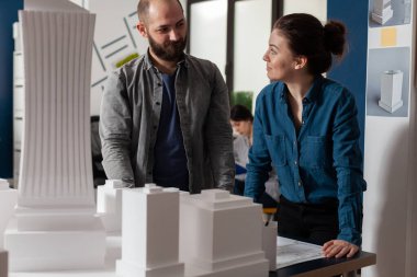 Mimarlar takım çalışması yapıyor. Birbirlerine bakıyorlar. Planları tartışıyorlar.