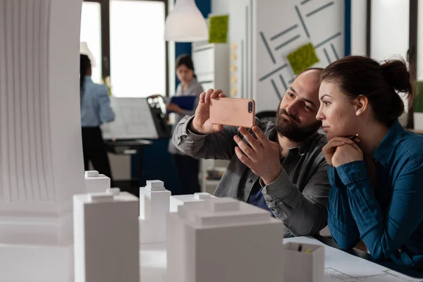 Arquitectos haciendo trabajo en equipo mirando el contenido móvil en el teléfono inteligente — Foto de Stock