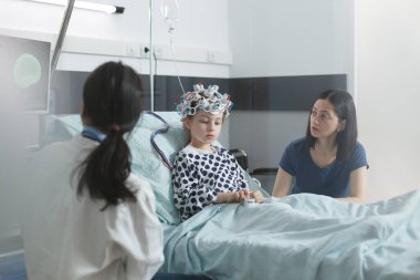 Klinik pediatri doktoru hasta küçük çocuğun EEG taramasının sonuçlarını pediatri koğuşu dinlenme odasında analiz ediyor..