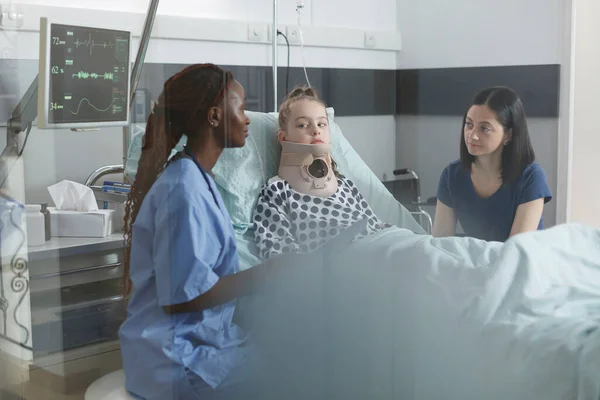 Pediatrische kliniek verpleegkundige analyseren van kleine meisje gezondheidstoestand tijdens het praten met bezorgde moeder — Stockfoto