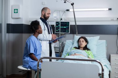 Hastane yatağında, serum ve hayati fonksiyonları olan bir kadına doktor tarafından danışıldı.