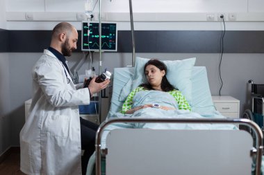 Doktor, iyileşen hastaya ameliyat sonrası tedavi için ilaç şişeleri sunuyor.