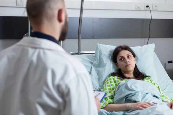 어깨 너머 병원 침대에서 산소를 재확인하는 여성의 모습 클립보드를 들고 있는 의사를 보면서 — 스톡 사진
