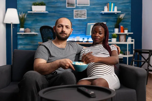 Future father offering pregnant african american woman a bowl of popcorn — Stock Photo, Image