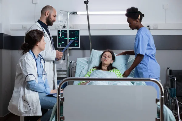 Woman with illness connected to iv drip line and monitor showing vitals recieving medical care — Stock Photo, Image