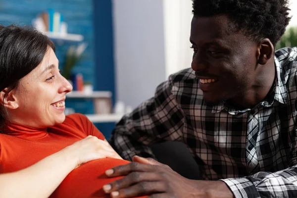 Fechar o sorriso interracial jovem casal esperando recém-nascido — Fotografia de Stock