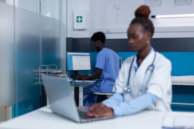 Hastane hemşiresi hasta kayıtlarını doğruluyor ve tedavi veritabanını güncelliyor.