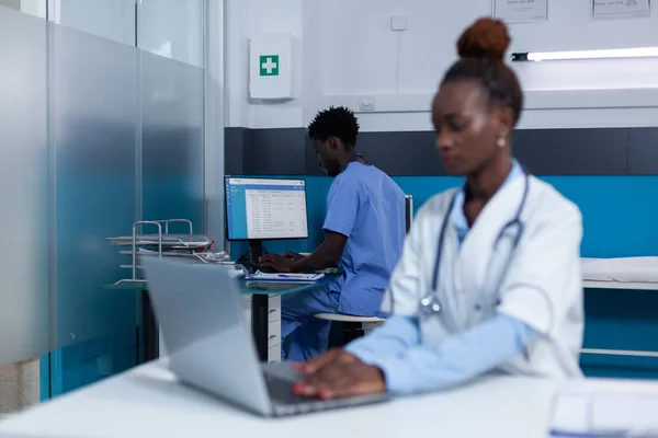 Infermiera ospedaliera che verifica le cartelle cliniche dei pazienti e aggiorna il database delle cure. — Foto Stock