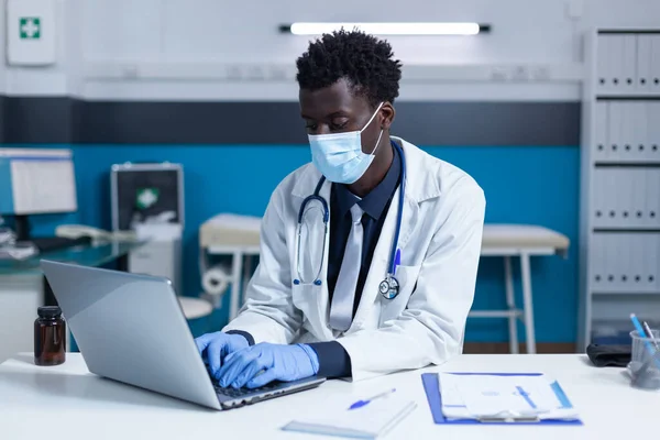 Médico clínico sentado no computador ao analisar relatos de doença e taxa de incidência covid — Fotografia de Stock